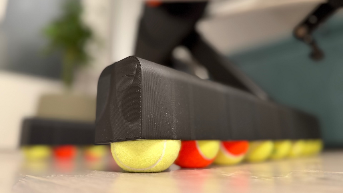 Row of tennis balls lined up benaeth a ROCKERON system with a blurred background