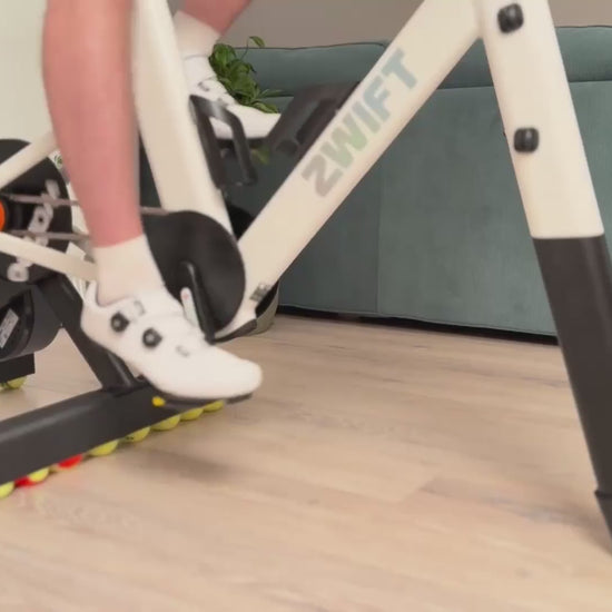 Zwift Ride smart frame on a Wahoo KICKR CORE 2 trainer moving naturally from side to side on ROCKERON rear adapters and a matching front support with colored motion balls.